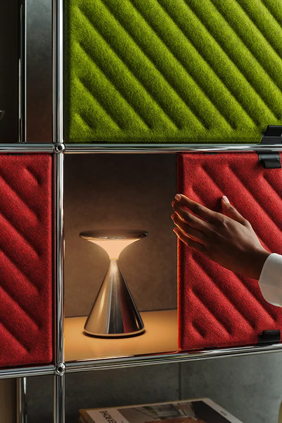 Offenes USM Haller Regalsystem in Weiß mit Kleiderstangen, Schubladen und Boxen vor blauer Wand.